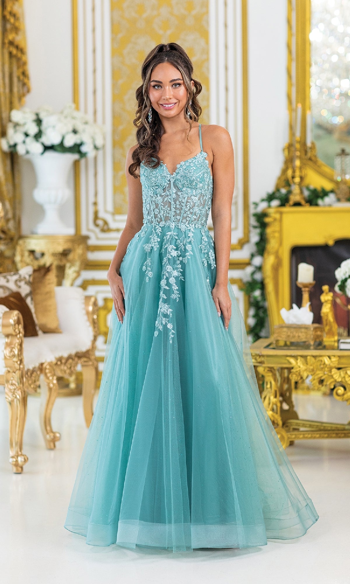 A woman wearing the Lace-Up Long Tulle Prom Ball Gown 4421 stands in an ornate room adorned with gold and white decor and elegant floral arrangements.